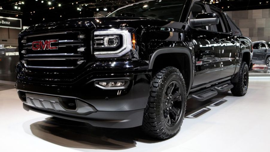 A black GMC Sierra pickup truck on display at an auto show.