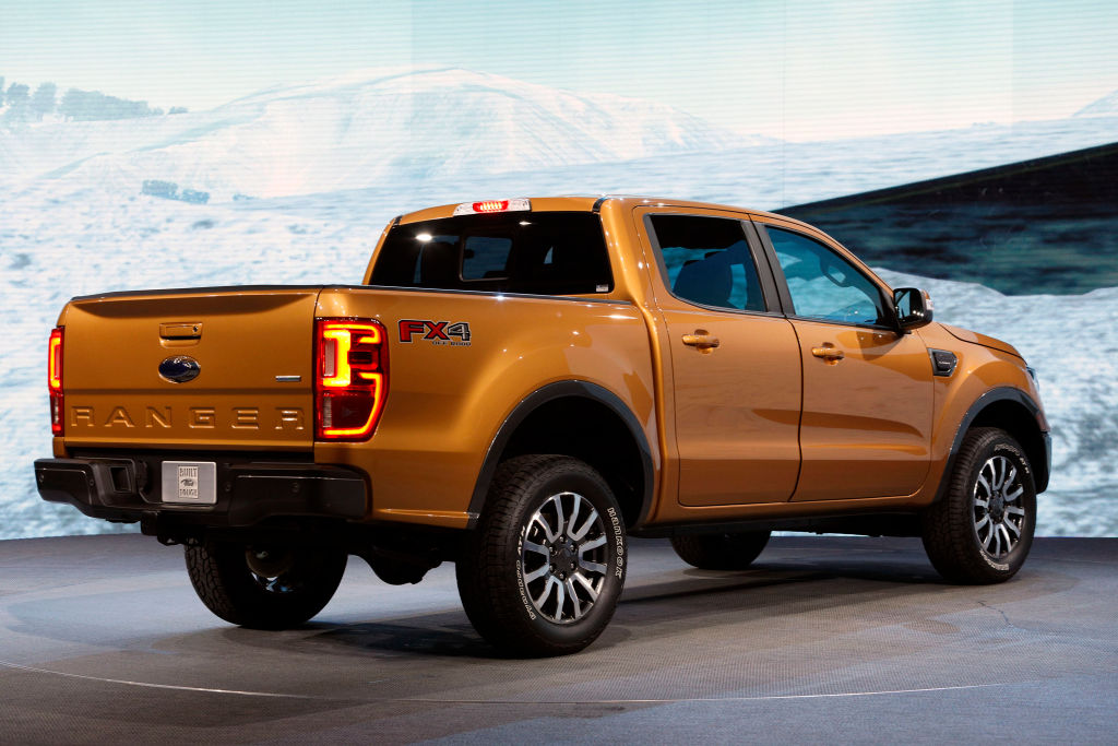A Ford Ranger in a shiny orange color on display at an auto show.