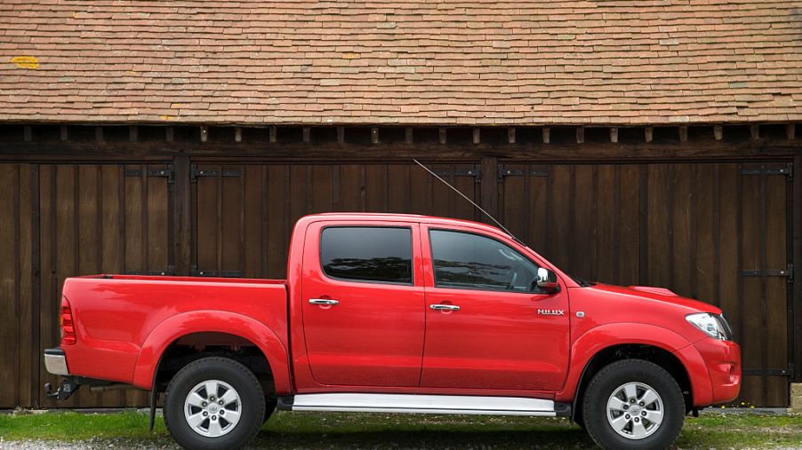 A red Toyota pickup truck parked in front of a fence.