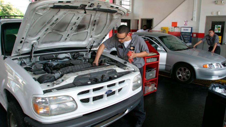A man servicing a truck by changing the oil.