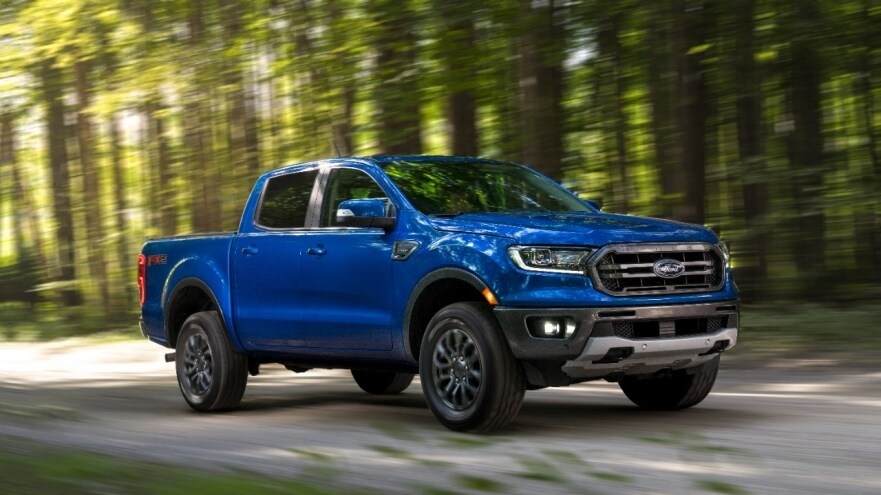 a blue 2019 ford ranger driving on a dirt road in the forest