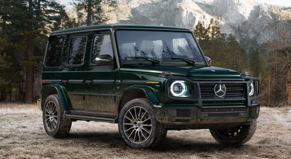 a mercedes-benz G-Class parked in the grass with mountains in the background