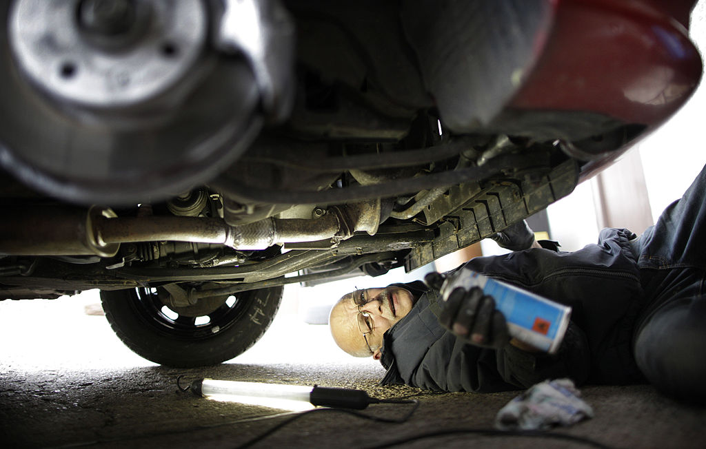 A man works on the under side of a car.