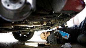 A man works on the under side of a car.