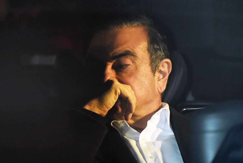 Former Renault Nissan CEO Carlos Ghosn in dark room looking down