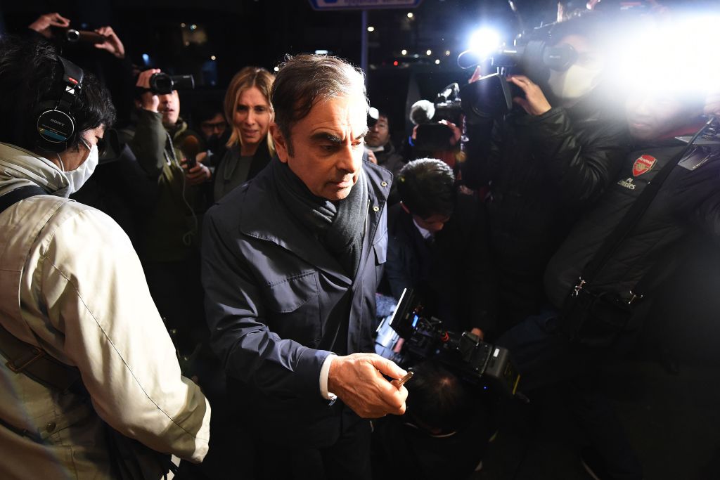 Carlos Ghosn in handcuffs being led out of the airport in Tokyo