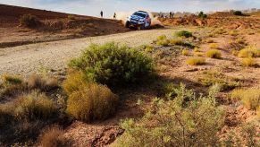 A Ford Baja Raptor racing through a desert terrain.