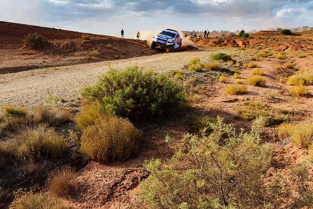 A Ford Baja Raptor racing through a desert terrain.