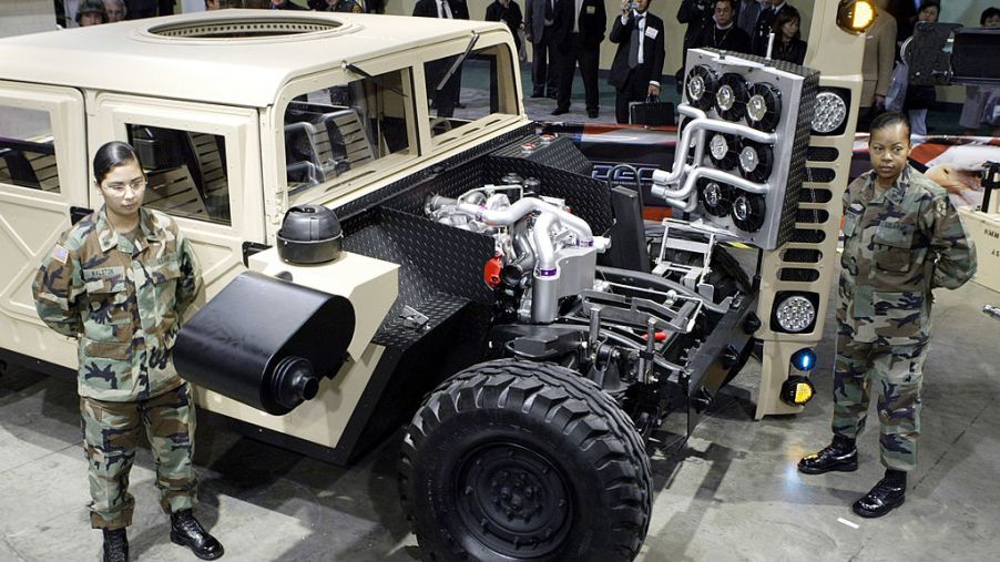 Two soldiers standing next to a military Humvee built by GM