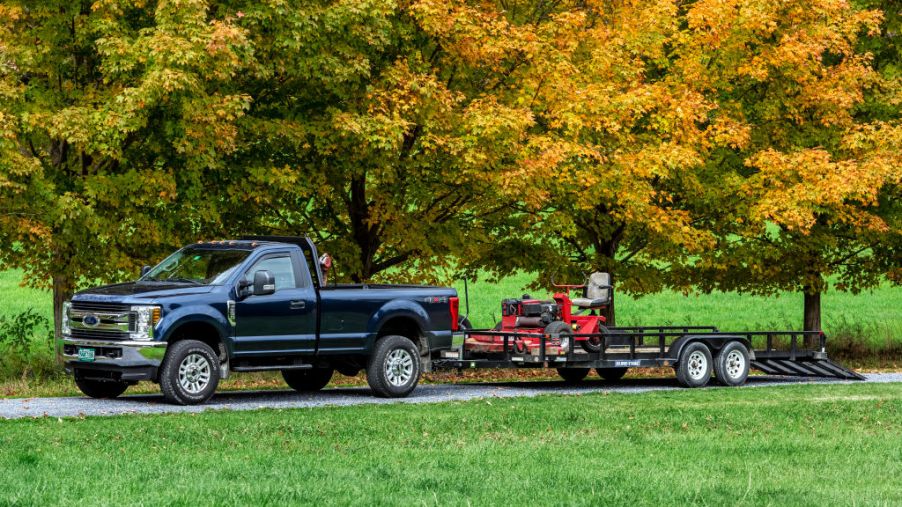 A lawn care service truck towing a lawn mower