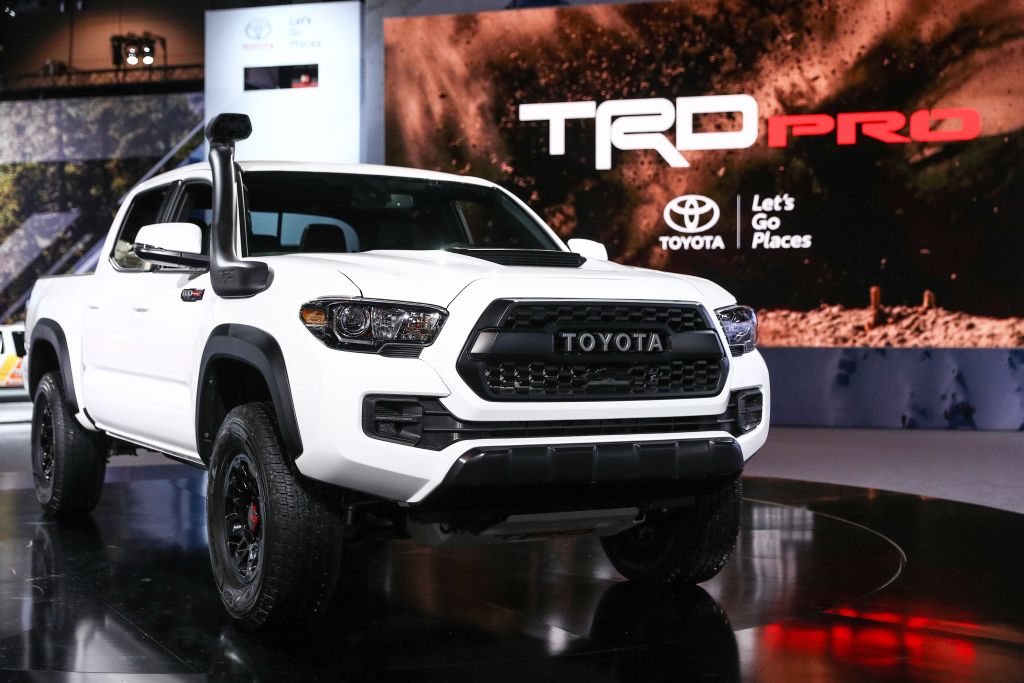 A Toyota Tacoma with white paint on display at an auto show.