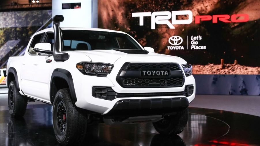 A Toyota Tacoma with white paint on display at an auto show.
