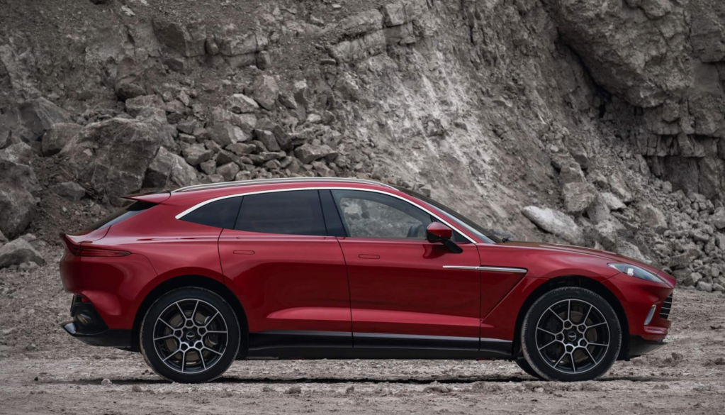 A red 2021 Aston Martin DBX SUV parked in a mountain setting.