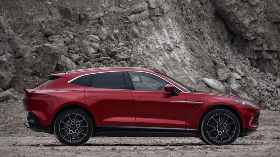 A red 2021 Aston Martin DBX SUV parked in a mountain setting.