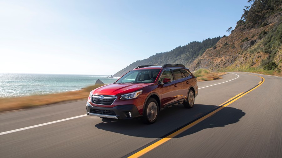 A red 2020 Subaru Outback driving on the countryside.