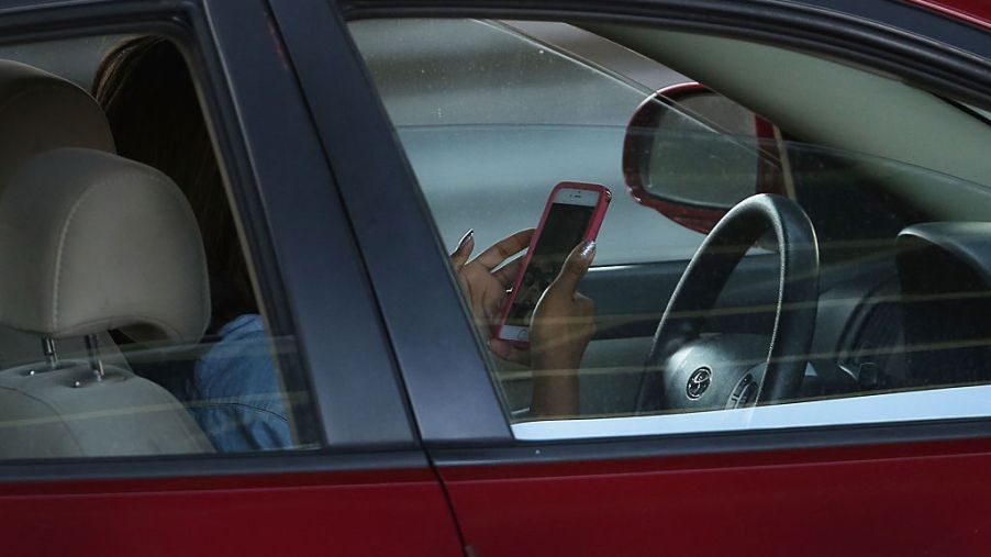 A bad driver using a phone while behind the wheel of a car