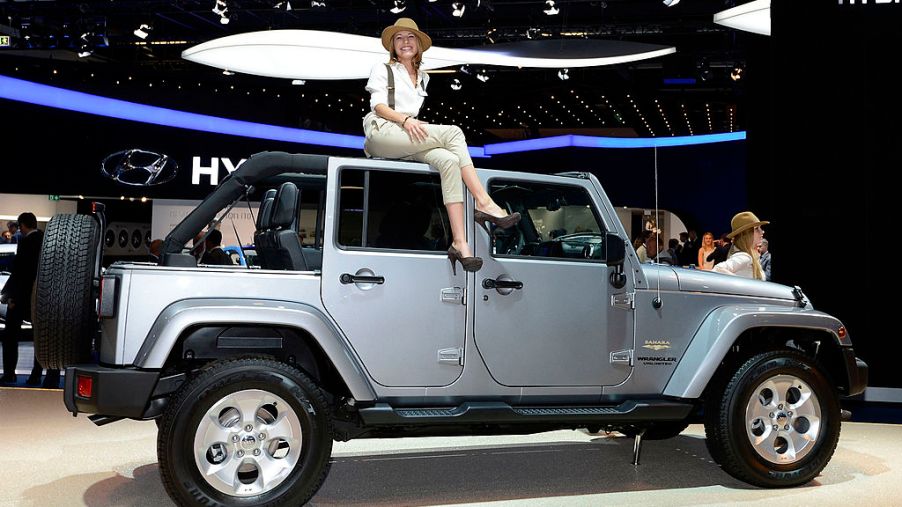A woman sits on top of a Jeep Wrangler