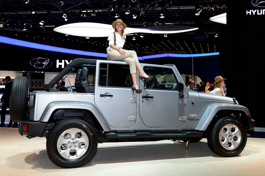 A woman sits on top of a Jeep Wrangler