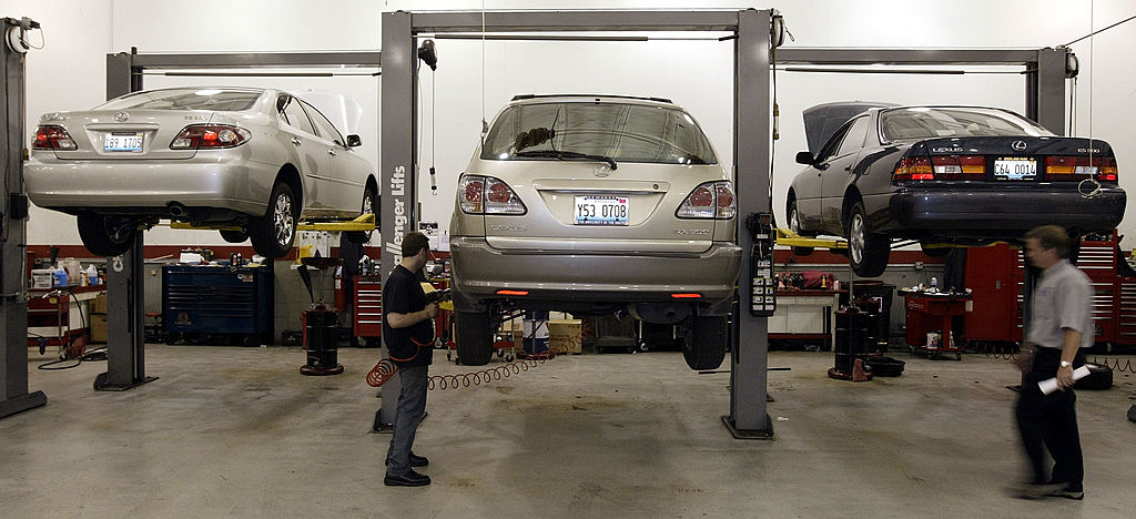 Mechanics perform maintenance on Lexus autos at a dealership.