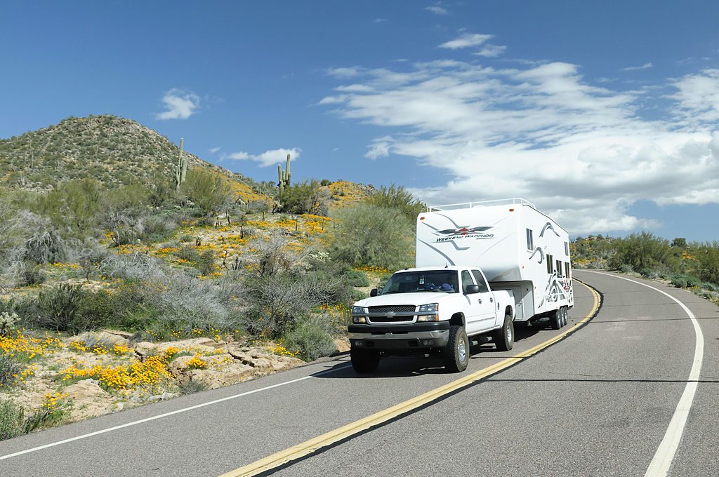 A truck towing a large RV down the road