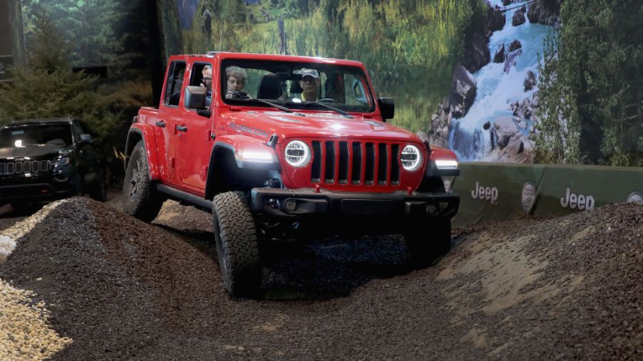 A person testing driving a Jeep Wrangler Rubicon at an auto show
