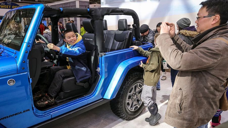 A family checking out a Jeep Wrangler SUV at an auto show