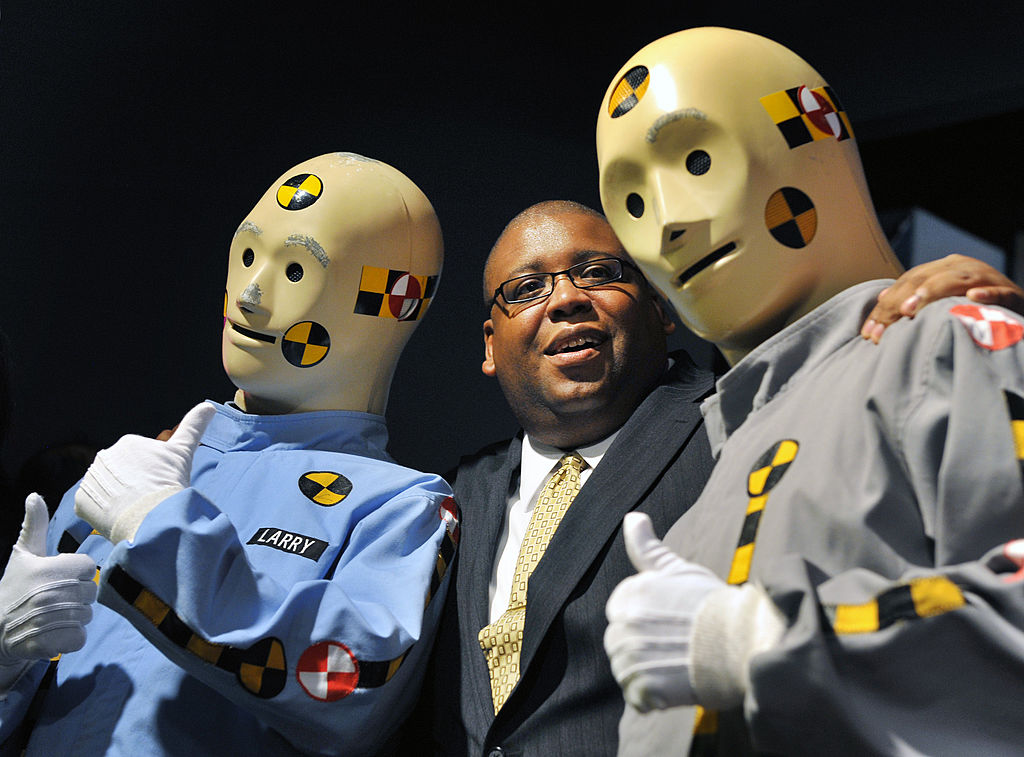 An NHTSA employee poses with crash test dummies