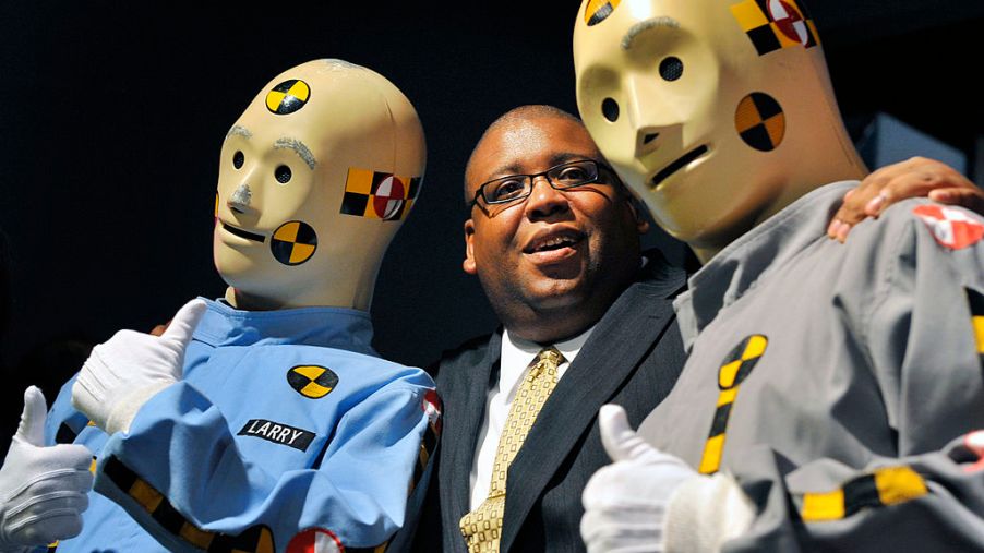 An NHTSA employee poses with crash test dummies