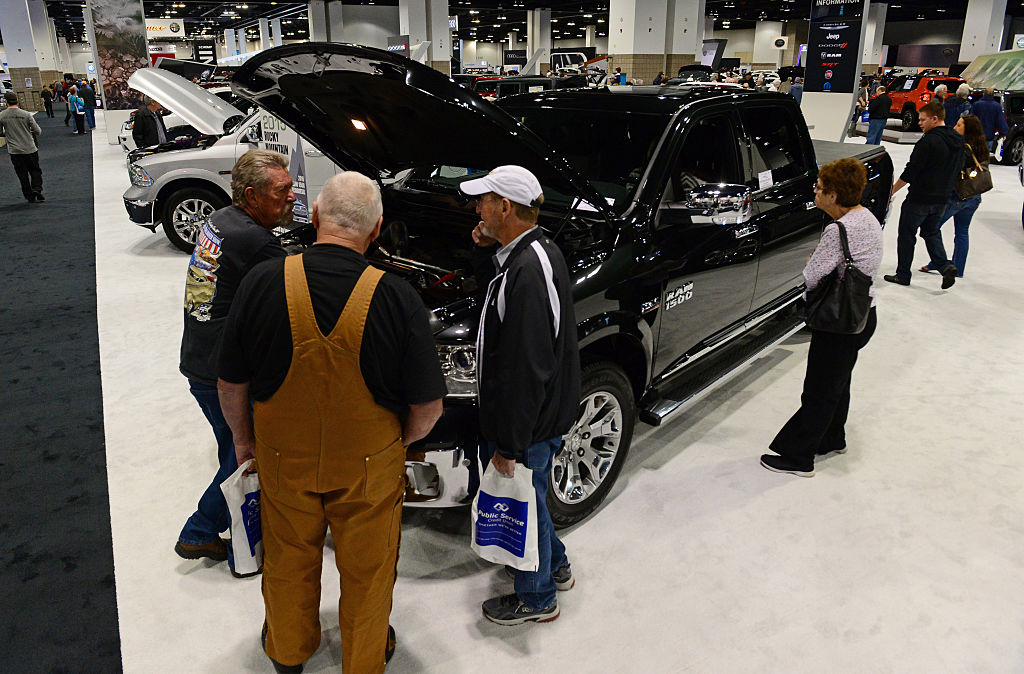 People walking around a Ram 1500 to inspect it