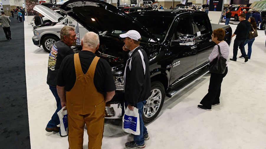 People walking around a Ram 1500 to inspect it