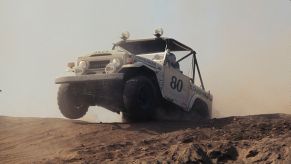 A Toyota FJ series truck jumps over a sand dune
