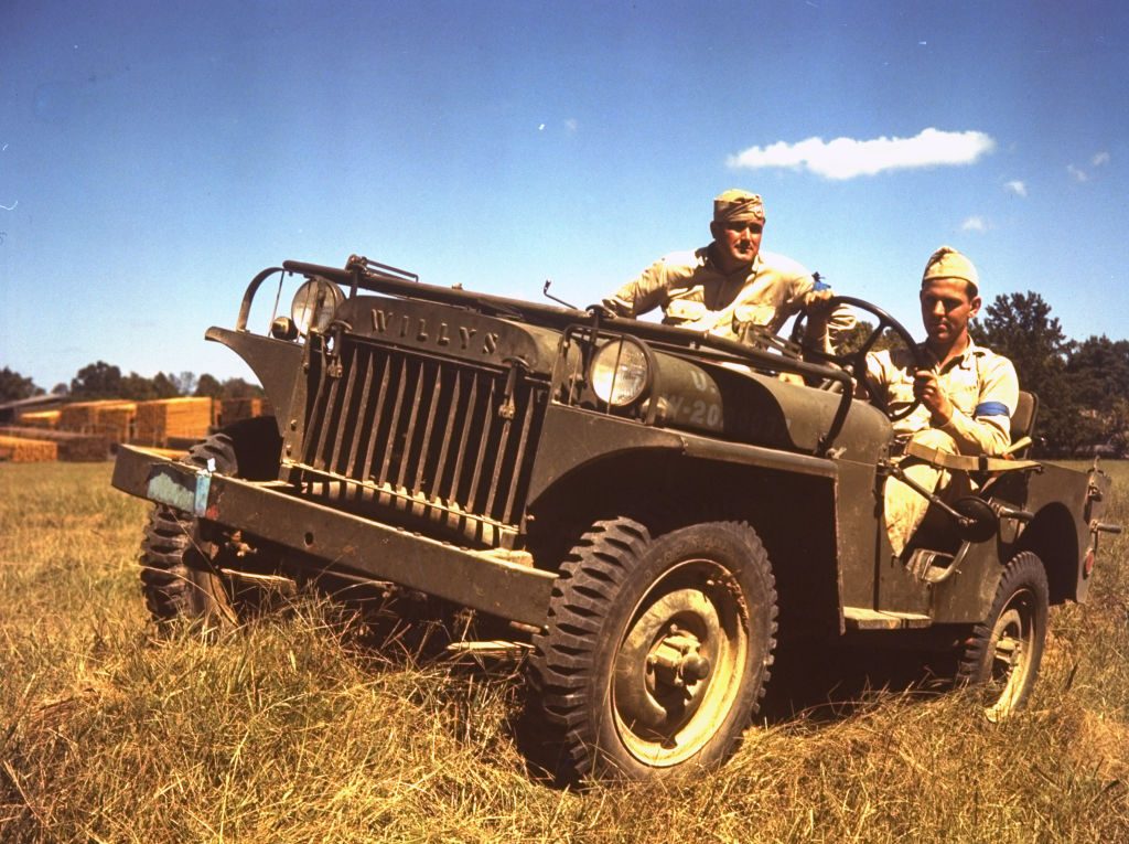 Two soldiers riding in a Willys Jeep