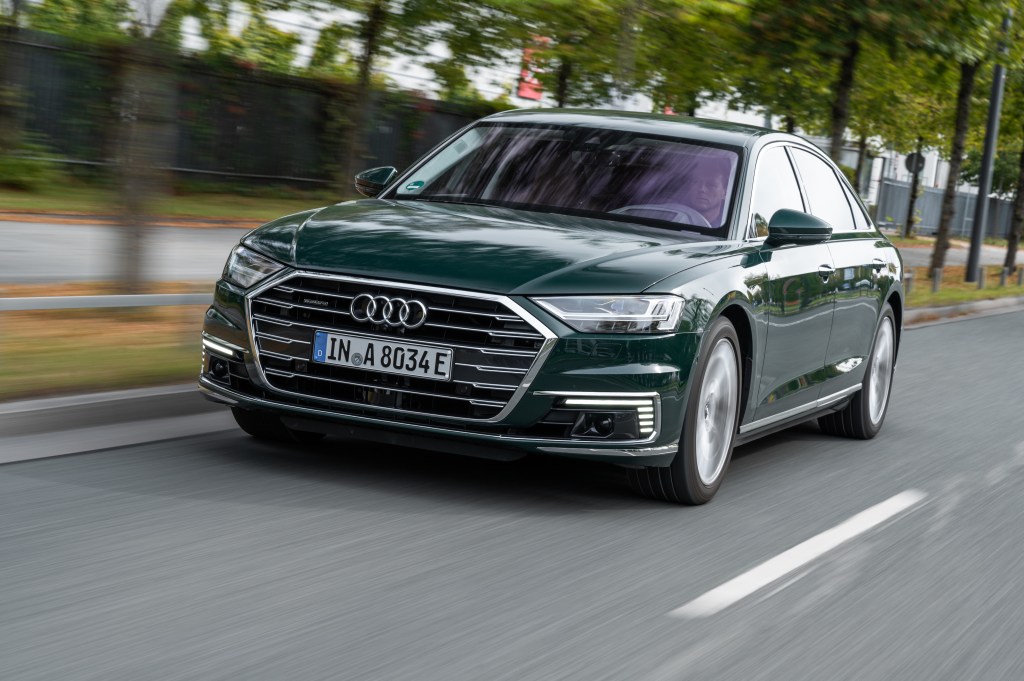 a green Audi A8 hybrid driving at speed on the road