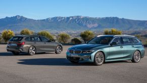 the BMW 3 series sedan and wagon parked on pavement with a scenic mountainous background