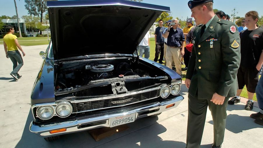 A solider walking by to check out a Chevy El Camino truck