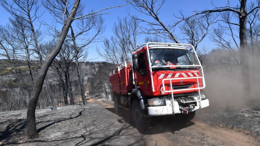 A fire truck drives through a burnt forest