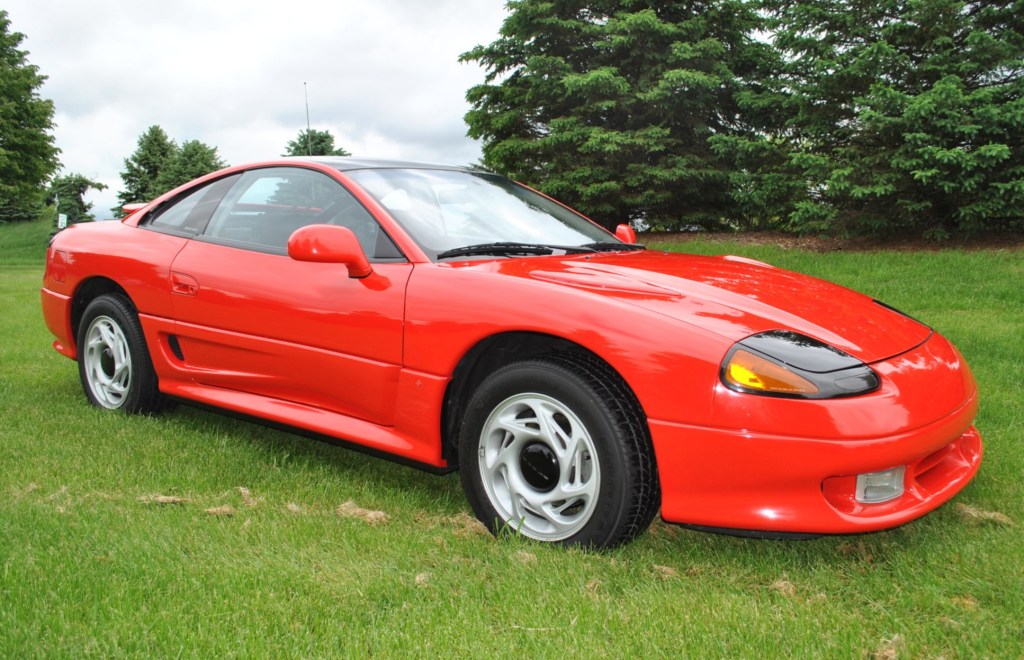A red 1991 Dodge Stealth R/T parked in a pretty grassy lawn.