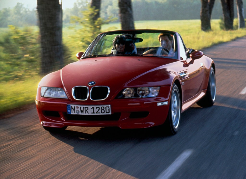 A red 1998 BMW Z3 M Roadster driving down a scenic country road.