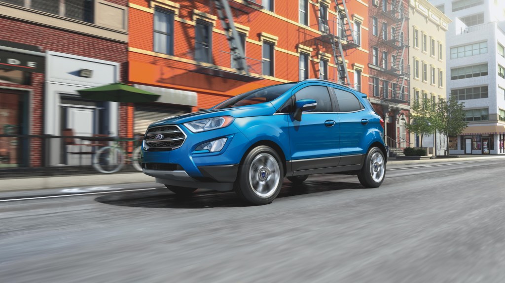 A blue 2020 Ford EcoSport crossover driving down an urban street.