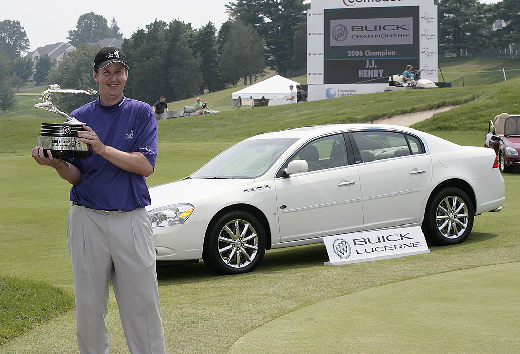 J.J. Henry stands in front of a Buick Lucerne with the trophy after winning the Buick Championship