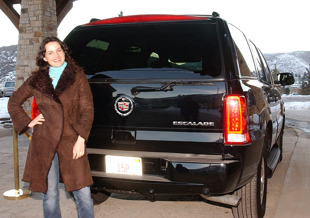 A women standing next to a Cadillac Escalade