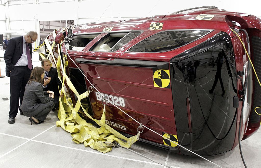 Workers examine an SUV after a crash test