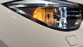 Close up photo of a front head lamp and illuminated turn signal on a white BMW