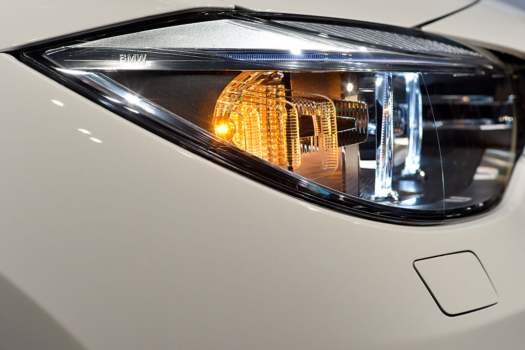 Close up photo of a front head lamp and illuminated turn signal on a white BMW