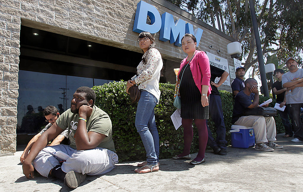 People wait in line outside of a DMV location.