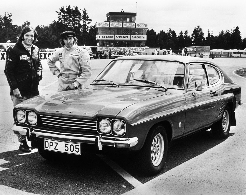 Race Car Drivers Jackie Steward and Emerson Fittipaldi standing in front of their Ford Capri.