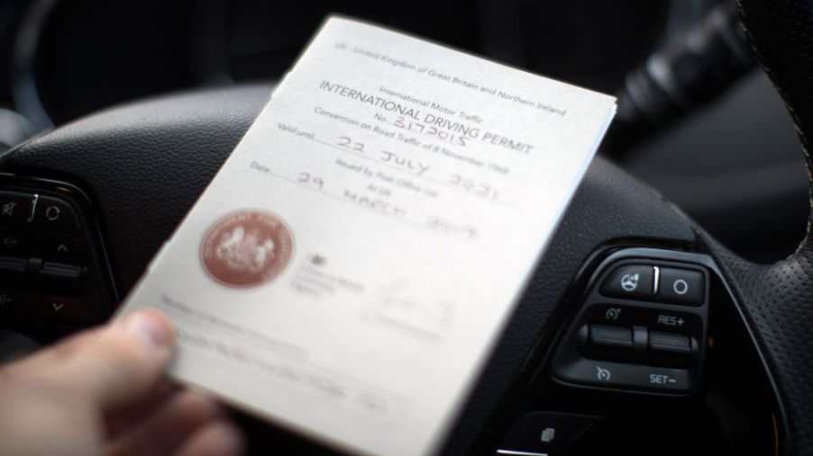 An International Driving Permit placed on top of a steering wheel.