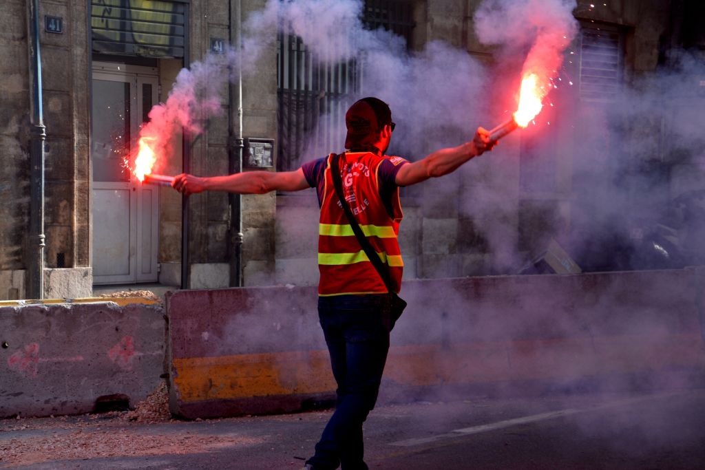 A man holds up emergency road flares to alert drivers of his disabled vehicle.