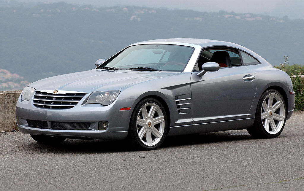 A silver 2003 Chrysler Crossfire coupe parked by a scenic outlook.
