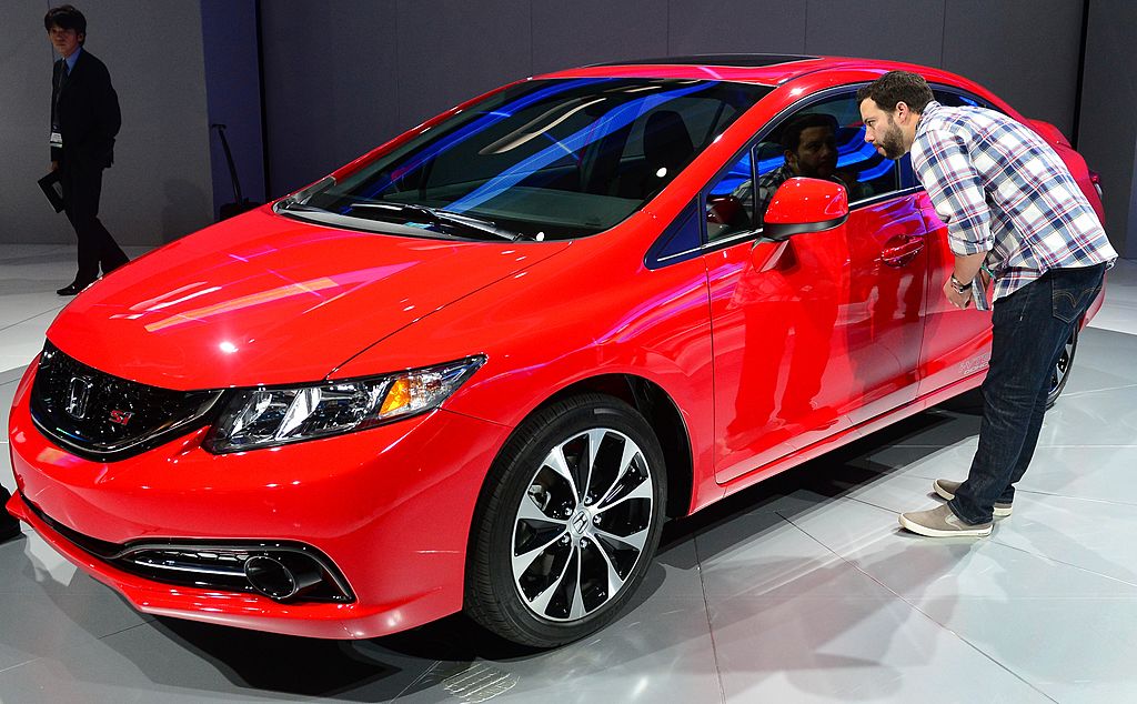 A man inspects a red 2013 Honda Civic Si Sedan at the L.A. Auto Show.